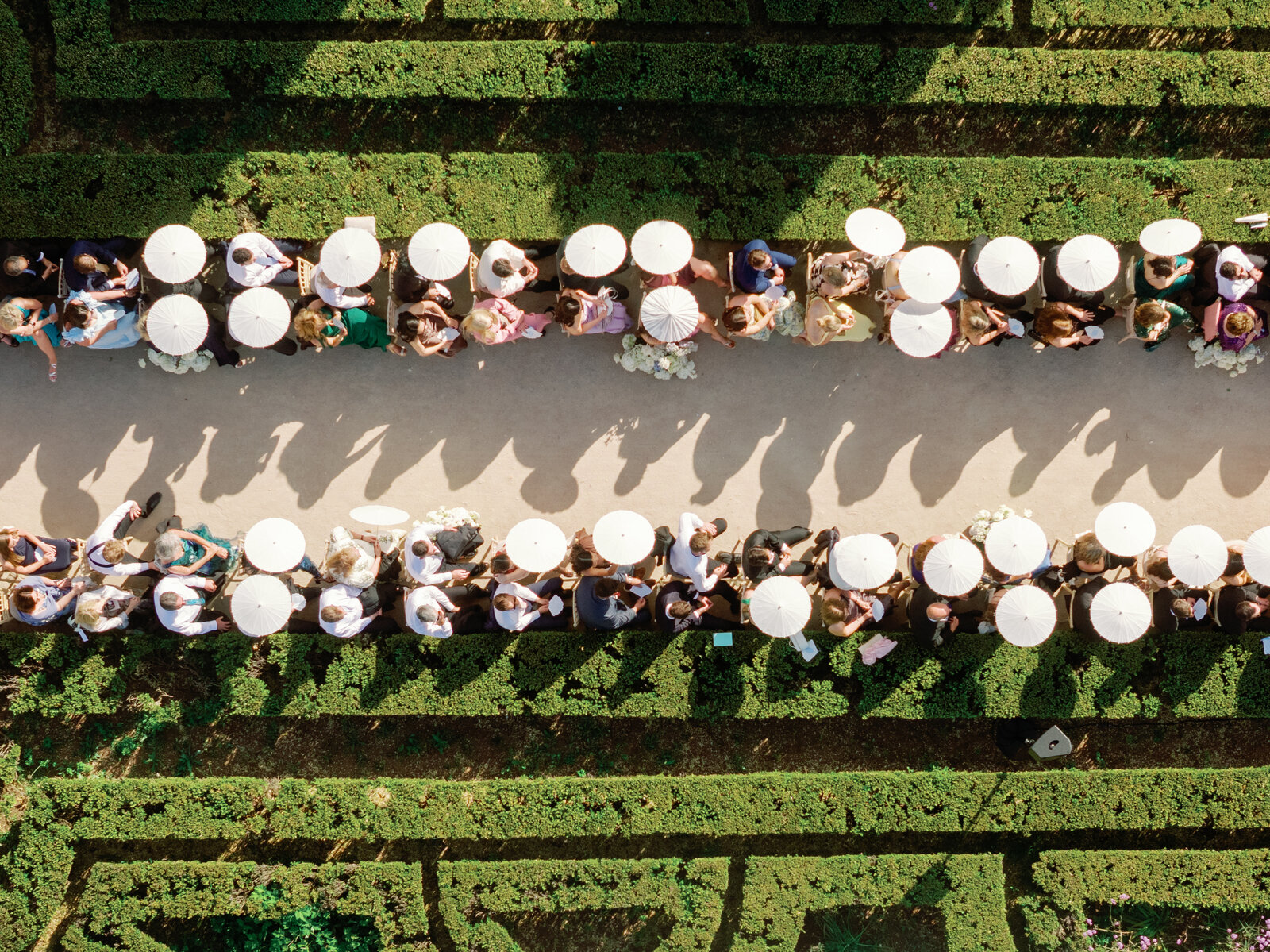 Top-down aerial view of guests seated along the aisle with umbrellas