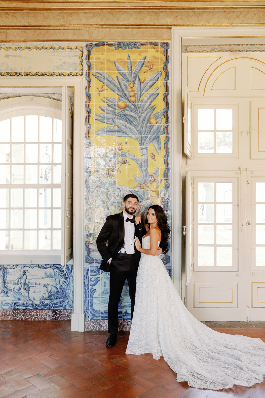 Bride and groom smiling against the azulejo tile mural