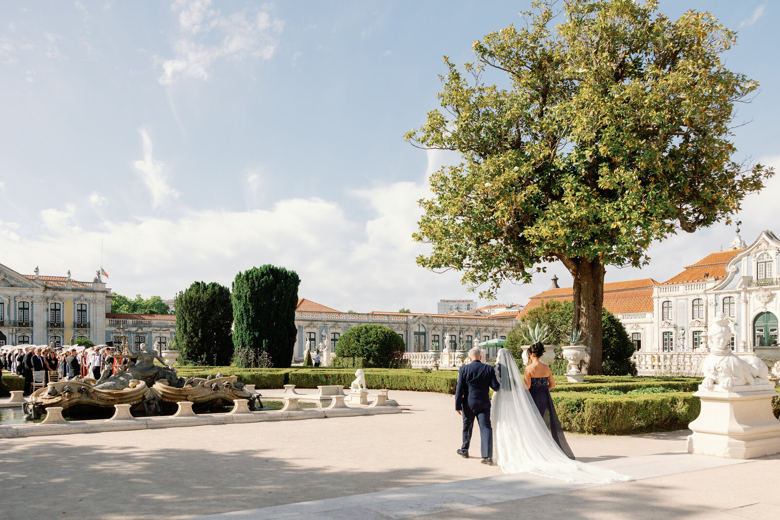 Bride walking with her father past the garden fountain