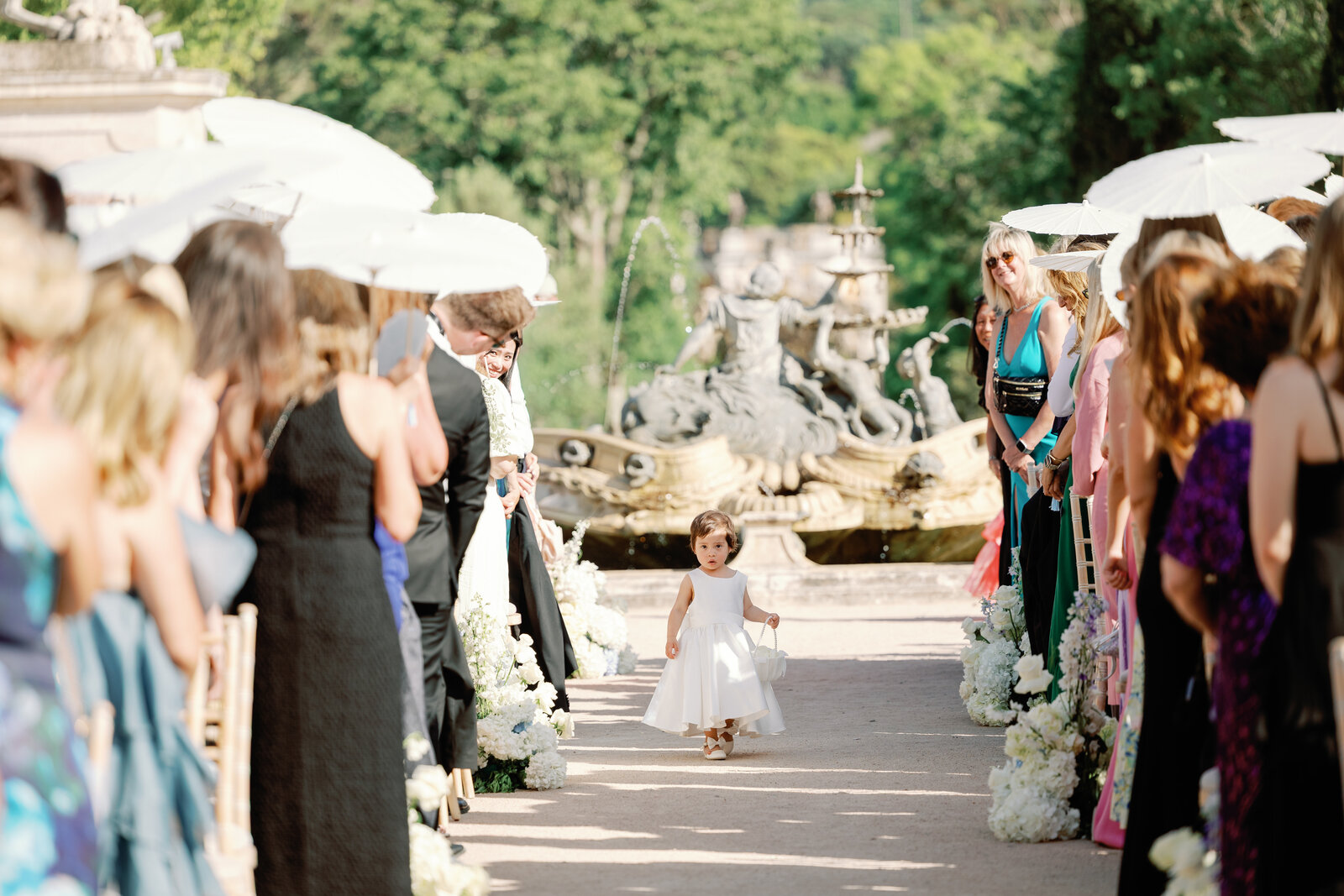 Flower girl walking down the aisle toward the fountain