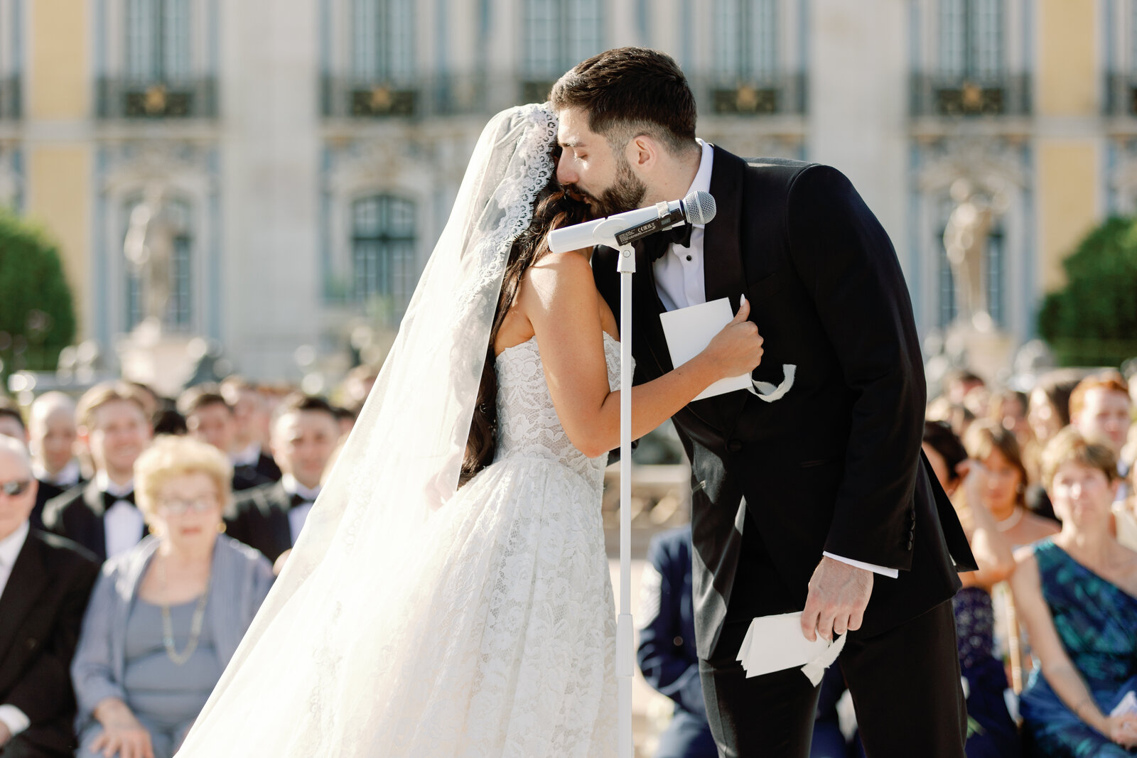 Groom kissing the bride's forehead at the microphone