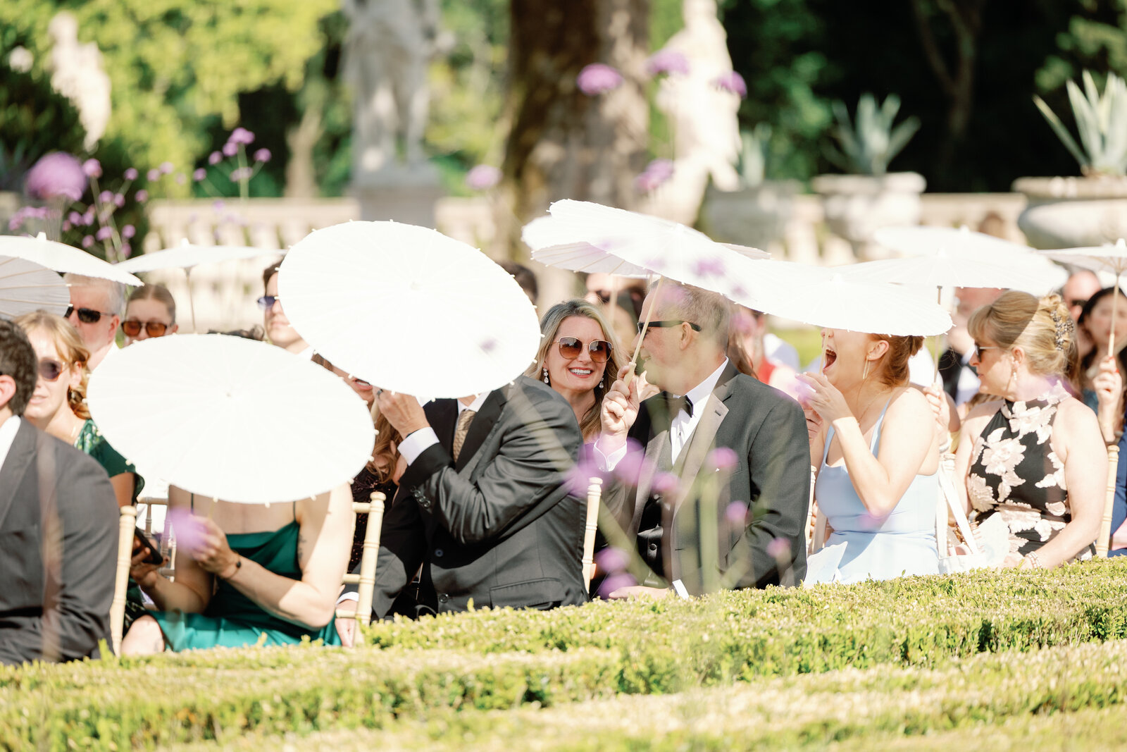 Guests smiling under parasols before the ceremony