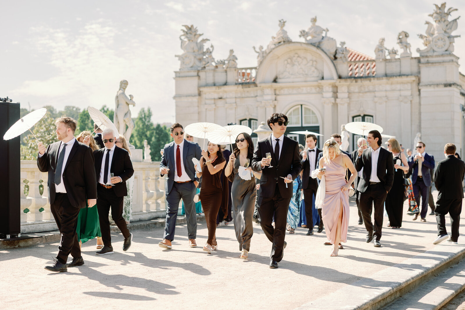 Guests walking through the palace grounds with parasols