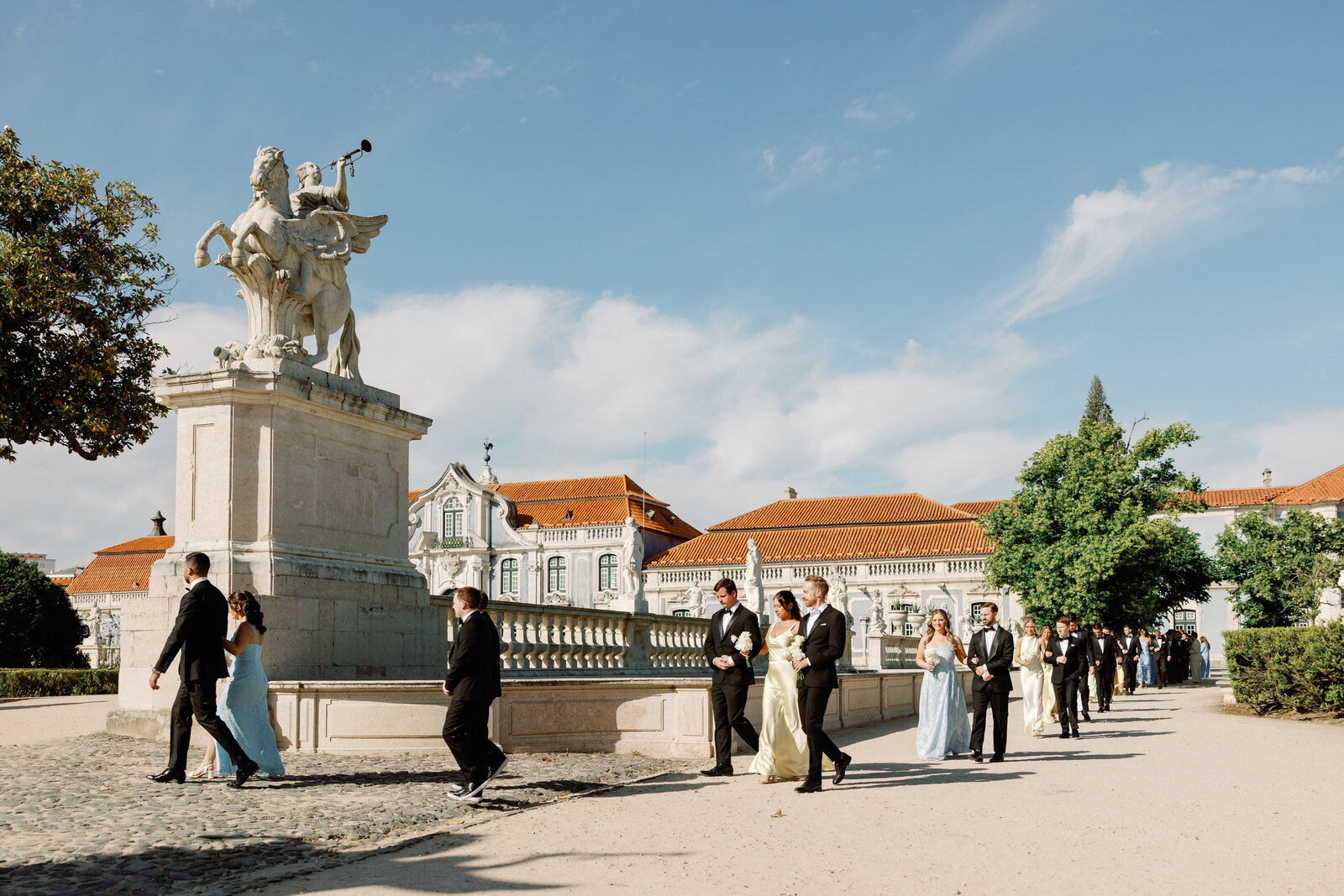 Wedding party walking past a statue toward the ceremony