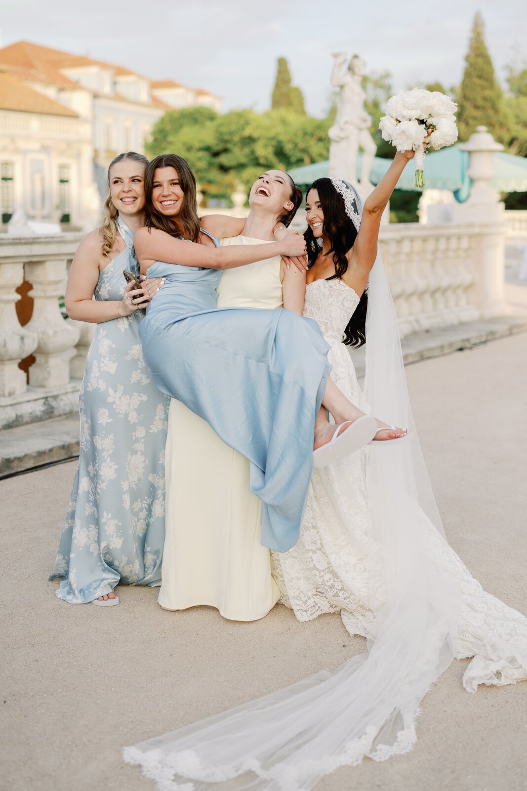 Bridesmaids laughing while carrying the bride between them