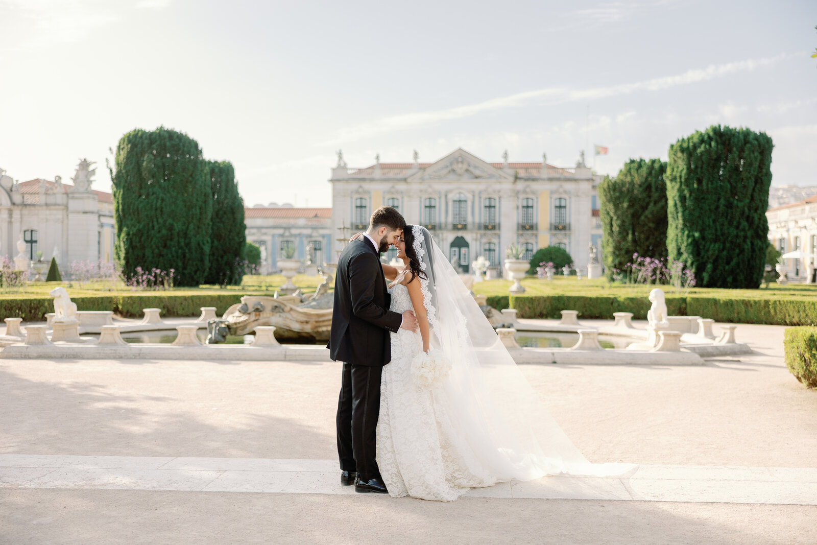 Bride and groom embracing in front of the palace fountain