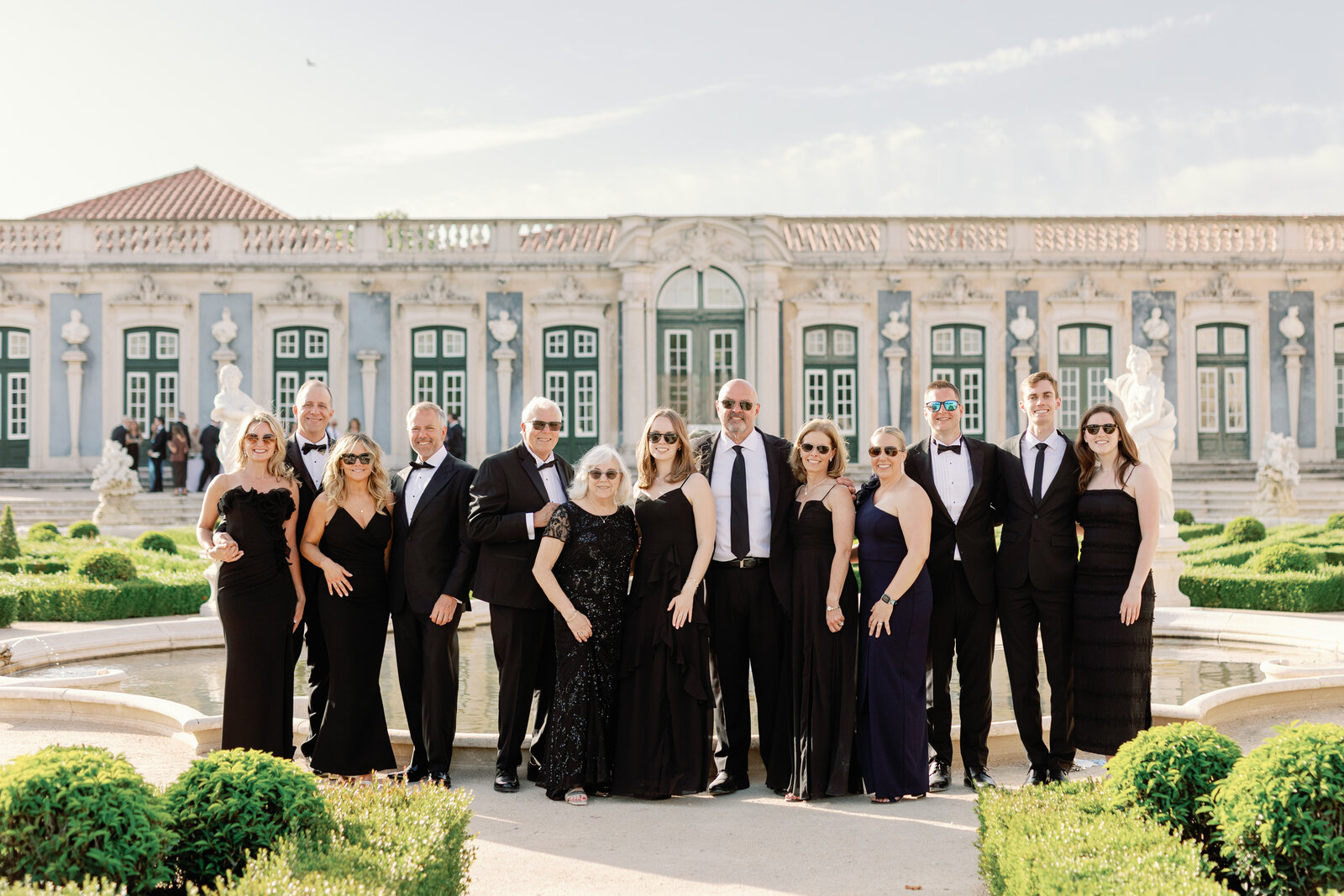 Extended family group portrait in black tie in front of the palace