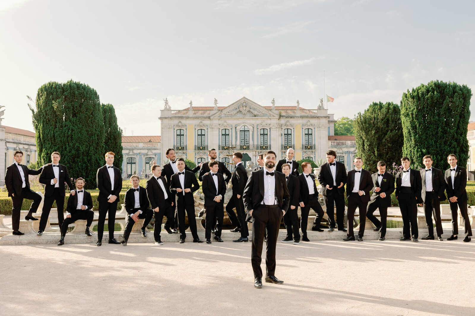 Groom and groomsmen gathered around the garden fountain
