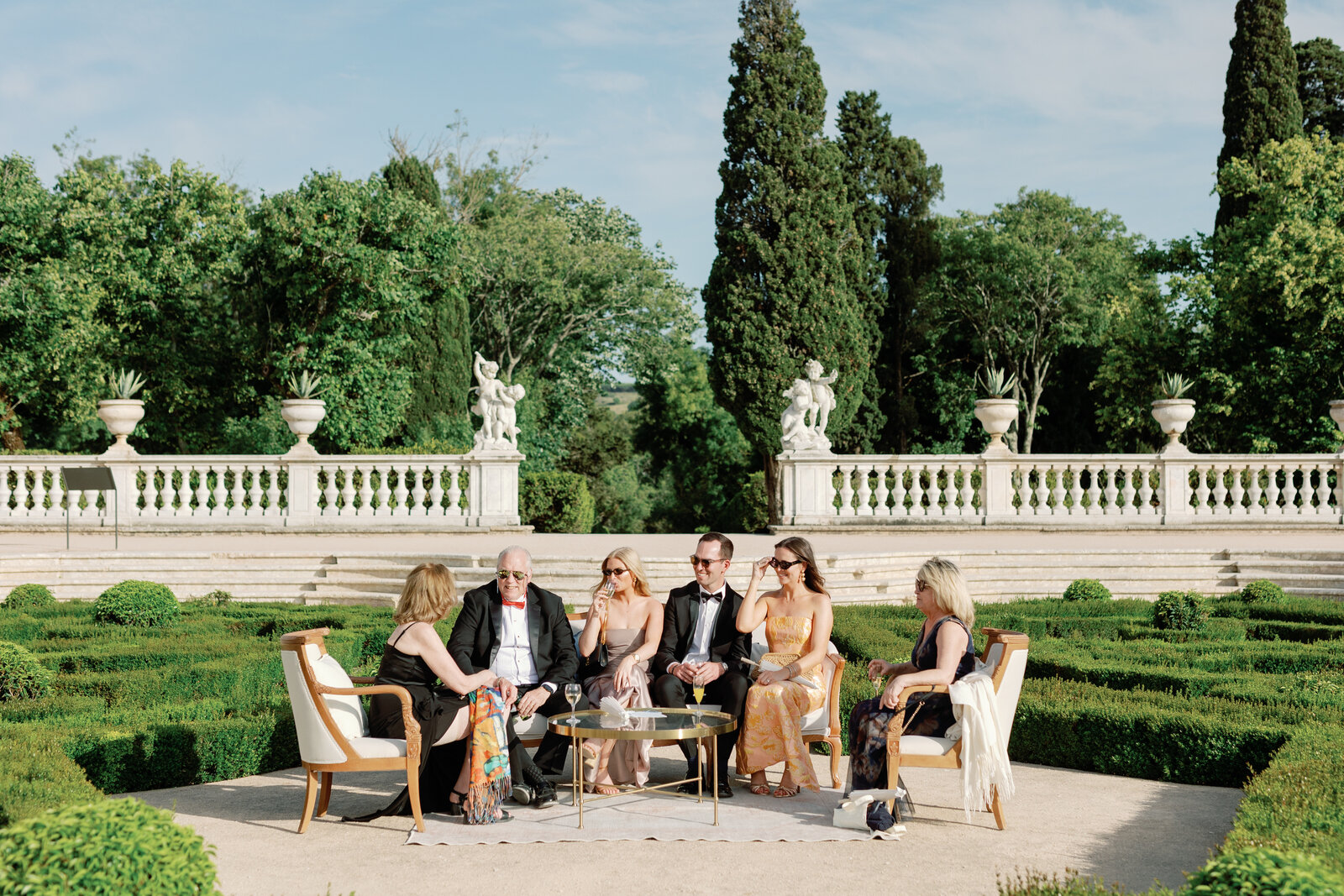 Guests relaxing in a lounge seating area amid the boxwood garden