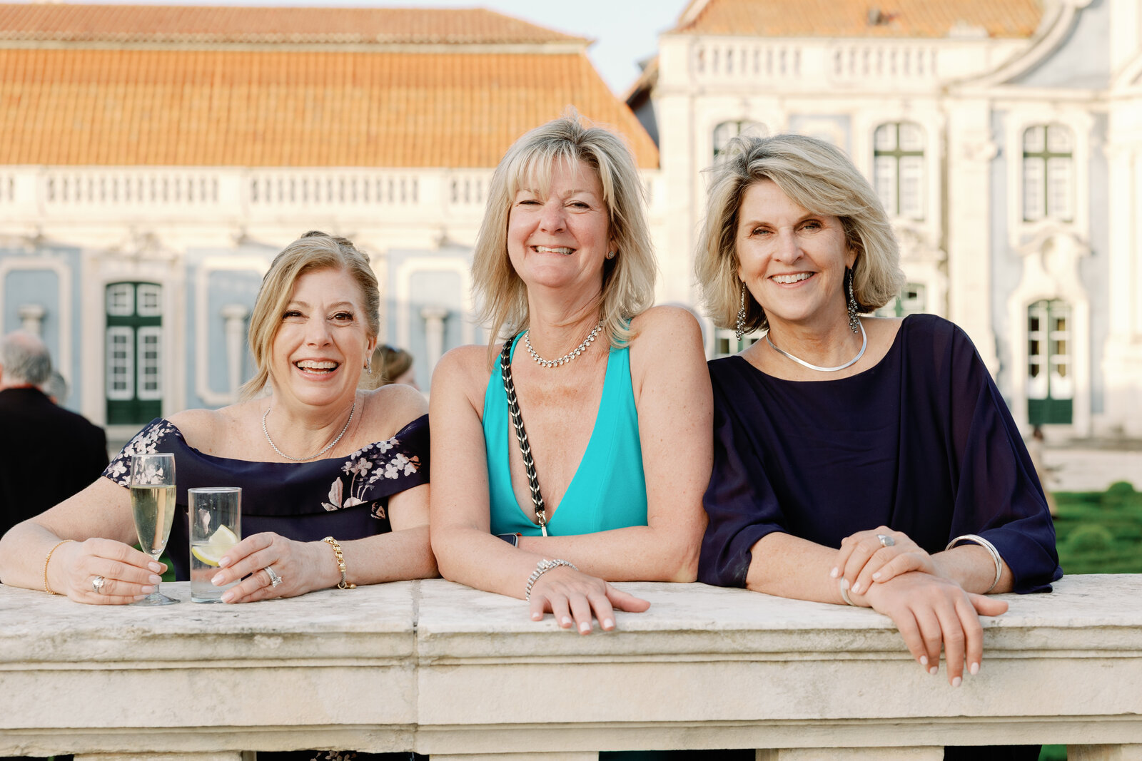 Three guests smiling together at the palace balustrade with drinks