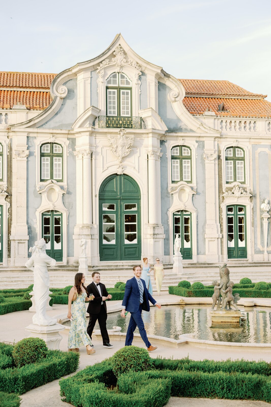 Guests walking past the garden fountain in front of the palace