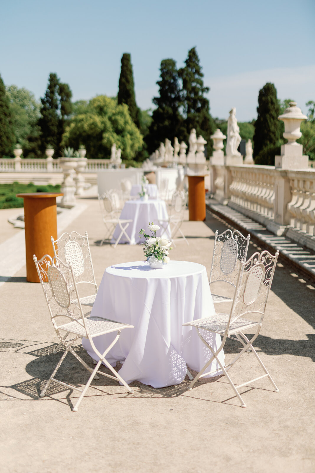 Bistro table with white linen and roses set along the palace balustrade