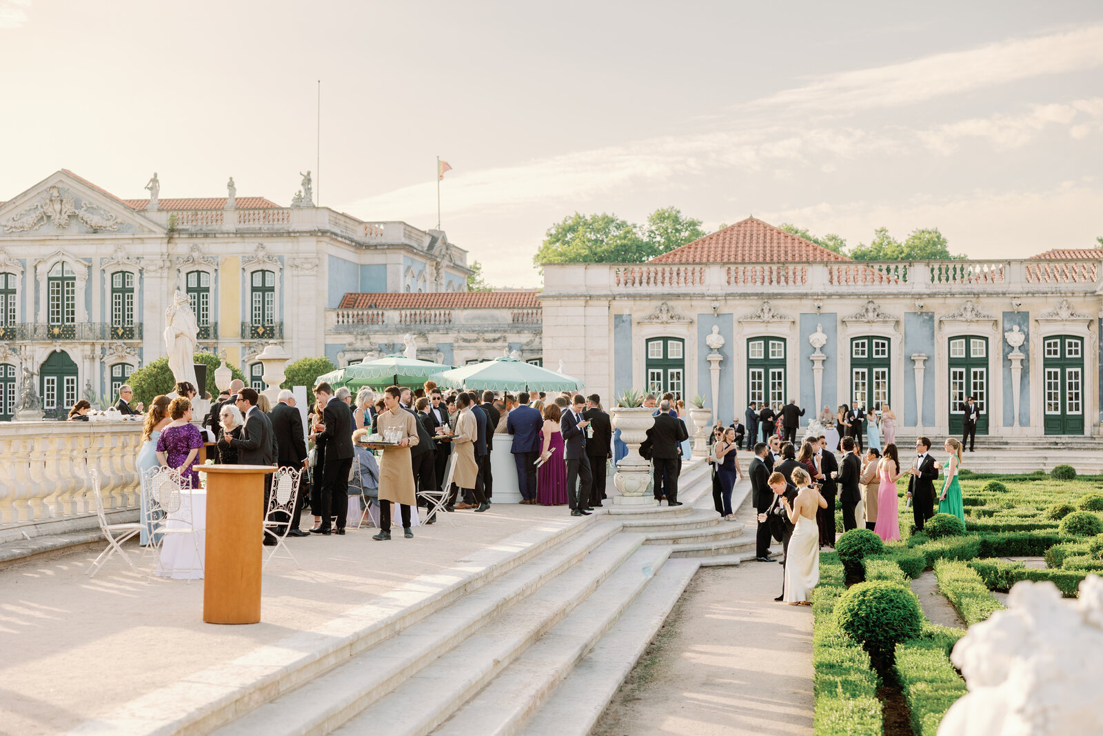 Wide view of the terrace with waiters serving guests under mint umbrellas