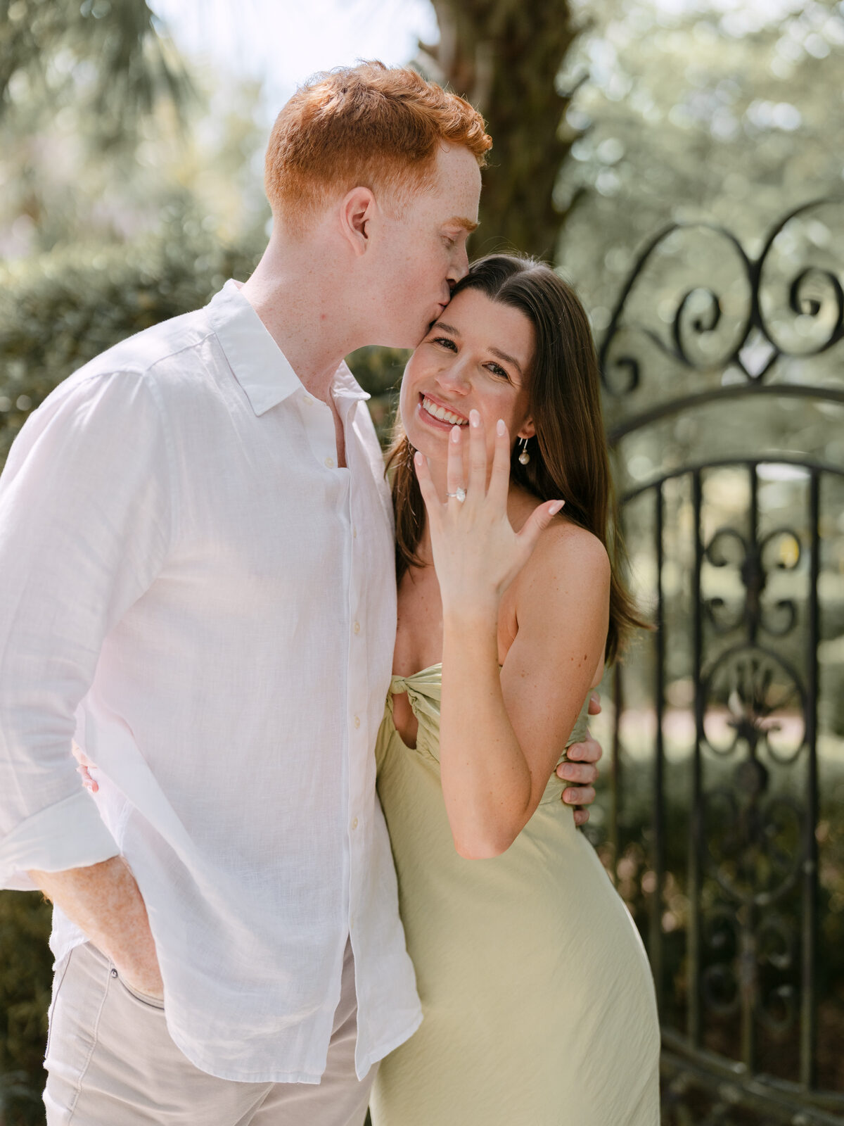 Couple sharing a kiss beside an iron garden gate