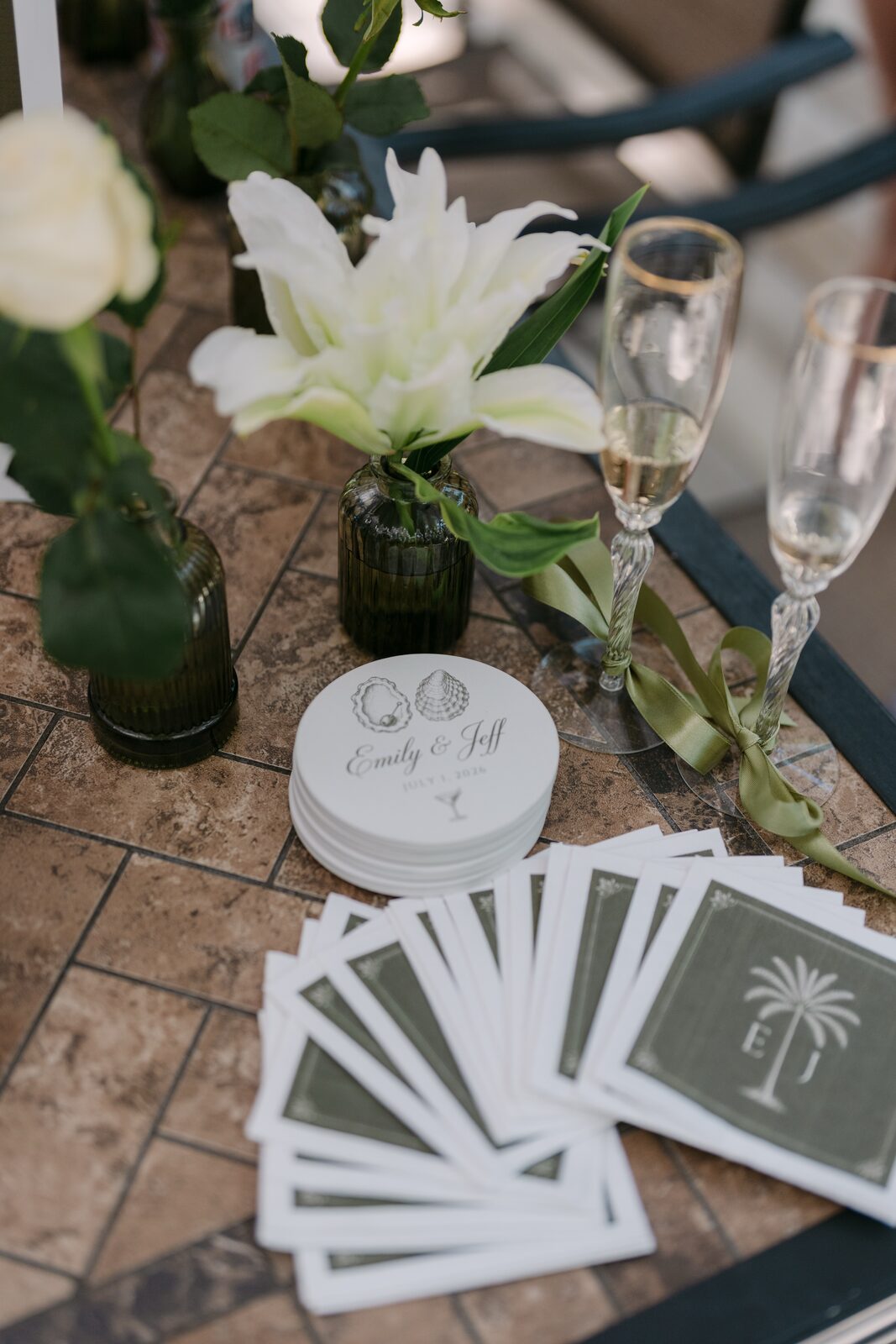 Flat lay of coasters, favors, and champagne flutes tied with ribbon