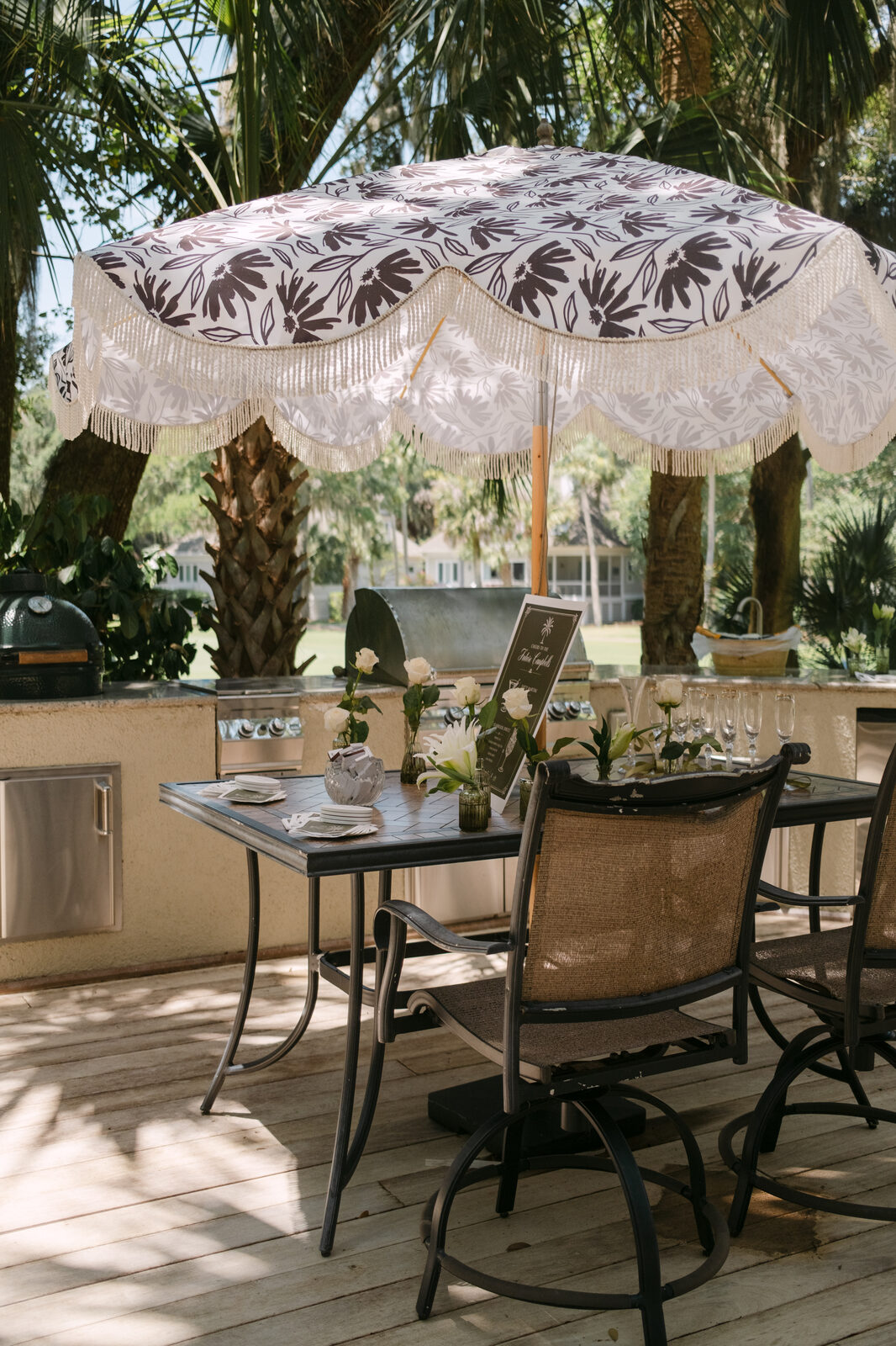 Patio table set for the engagement gathering beneath a fringed umbrella