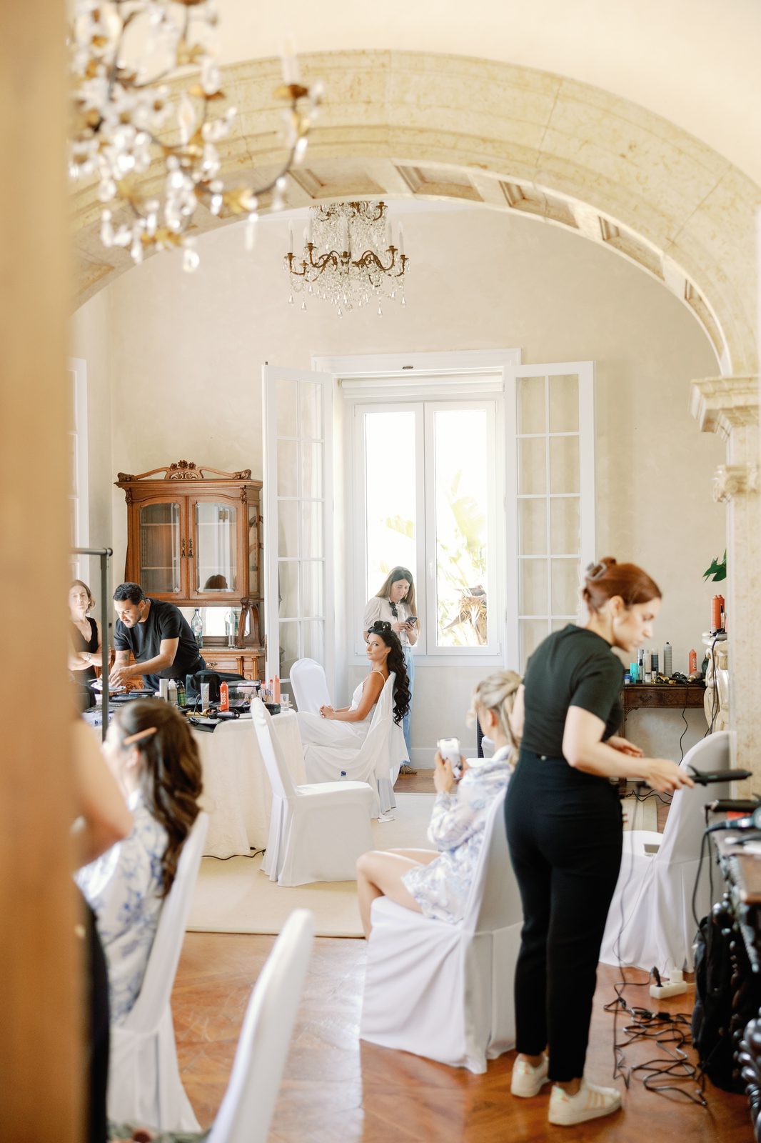 Bride getting ready in a sunlit room with a chandelier