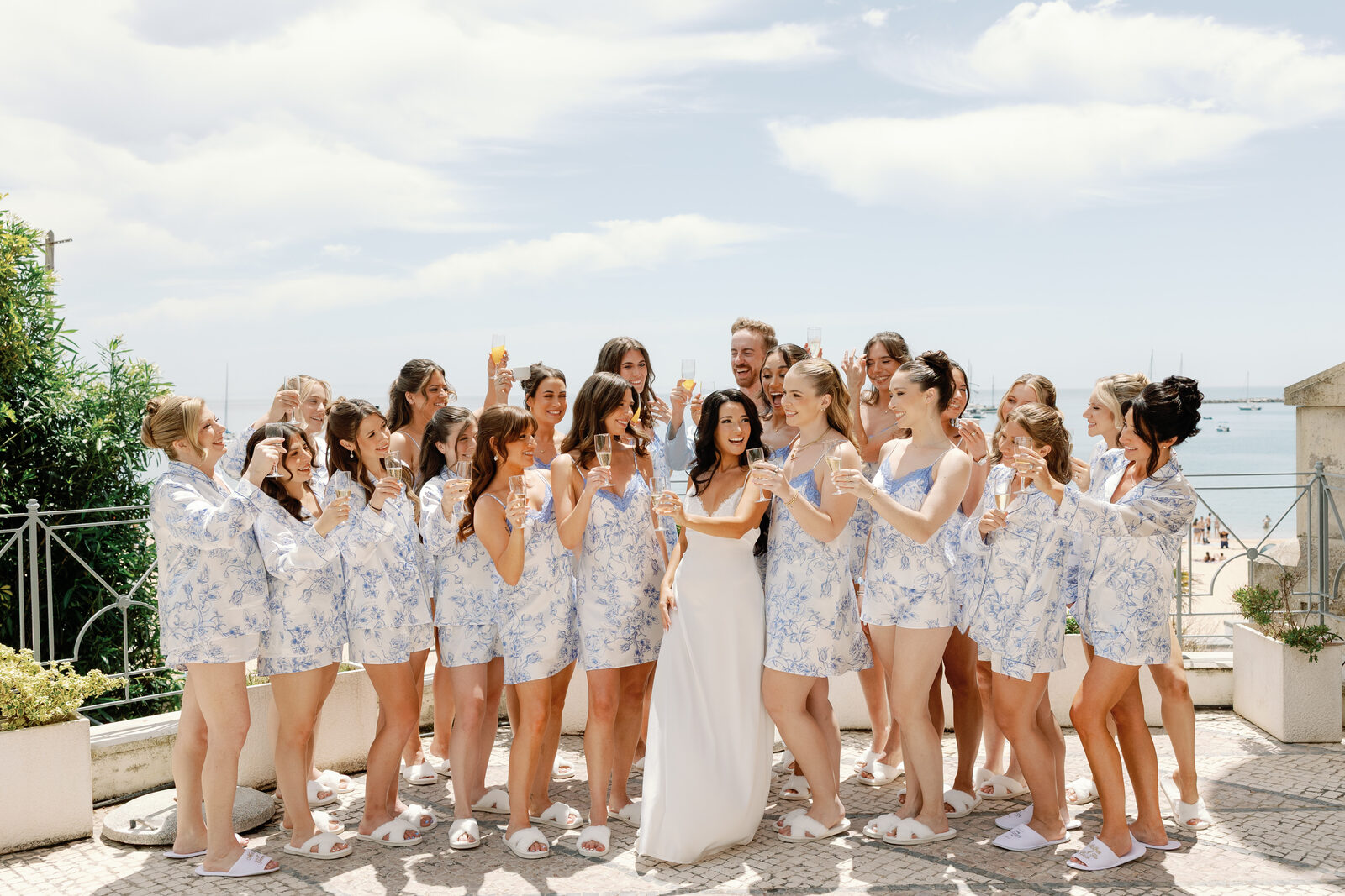 Bridesmaids raising champagne glasses on a seaside terrace