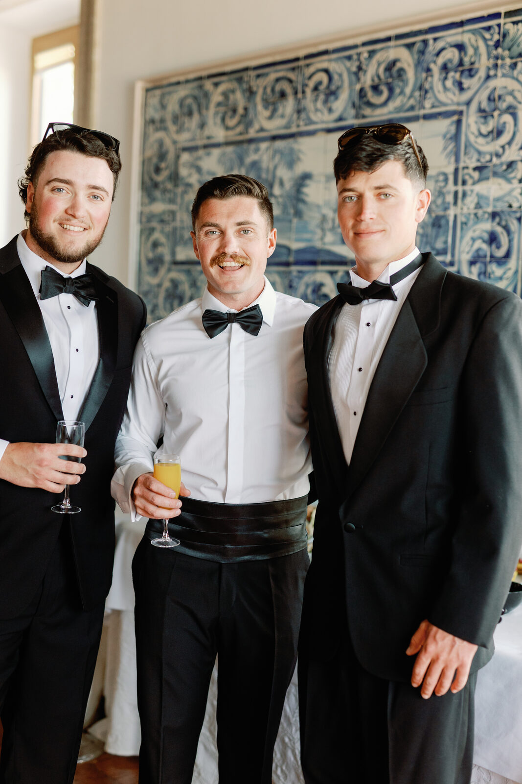 Three groomsmen laughing together with champagne