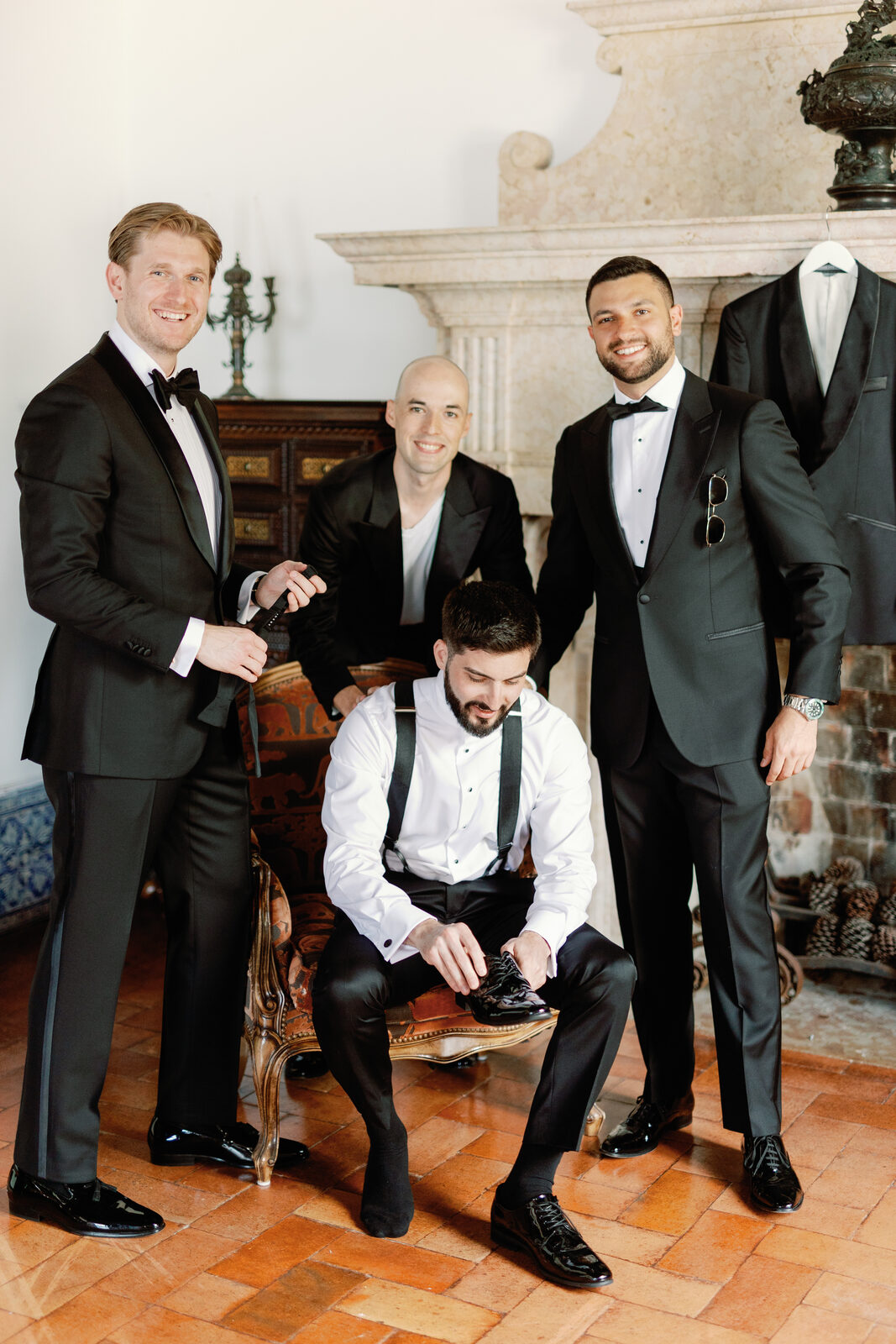 Groomsmen helping lace up shoes before the ceremony