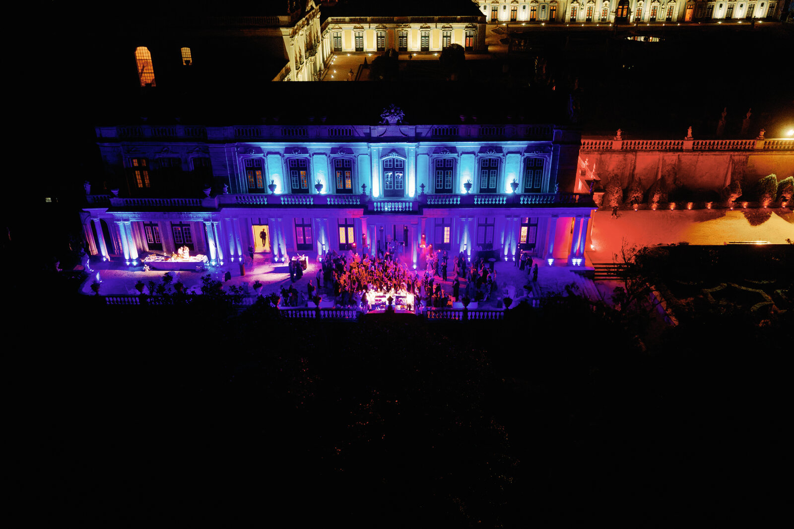 Aerial view of the palace lit in purple and blue with the dance floor crowd below