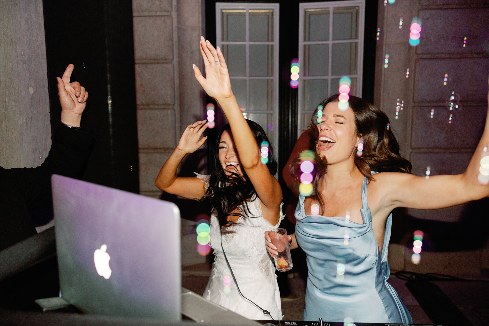 Bride and bridesmaid dancing by the DJ booth with bubbles floating around