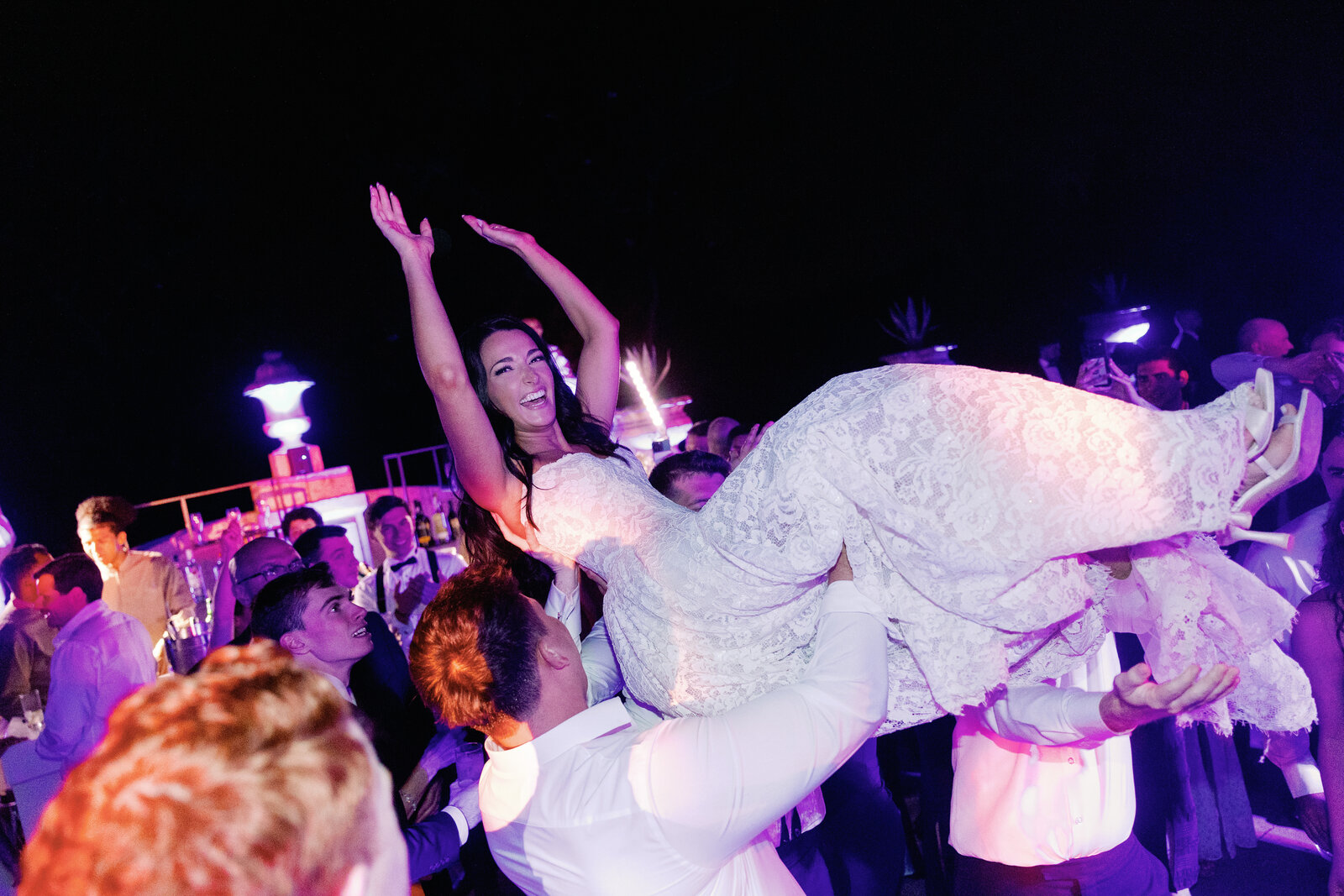 Bride lifted overhead by the crowd with arms raised