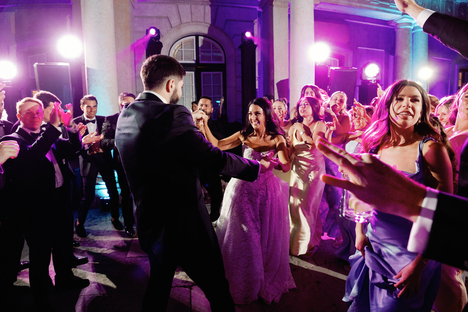Bride dancing with the groom surrounded by a clapping crowd of guests