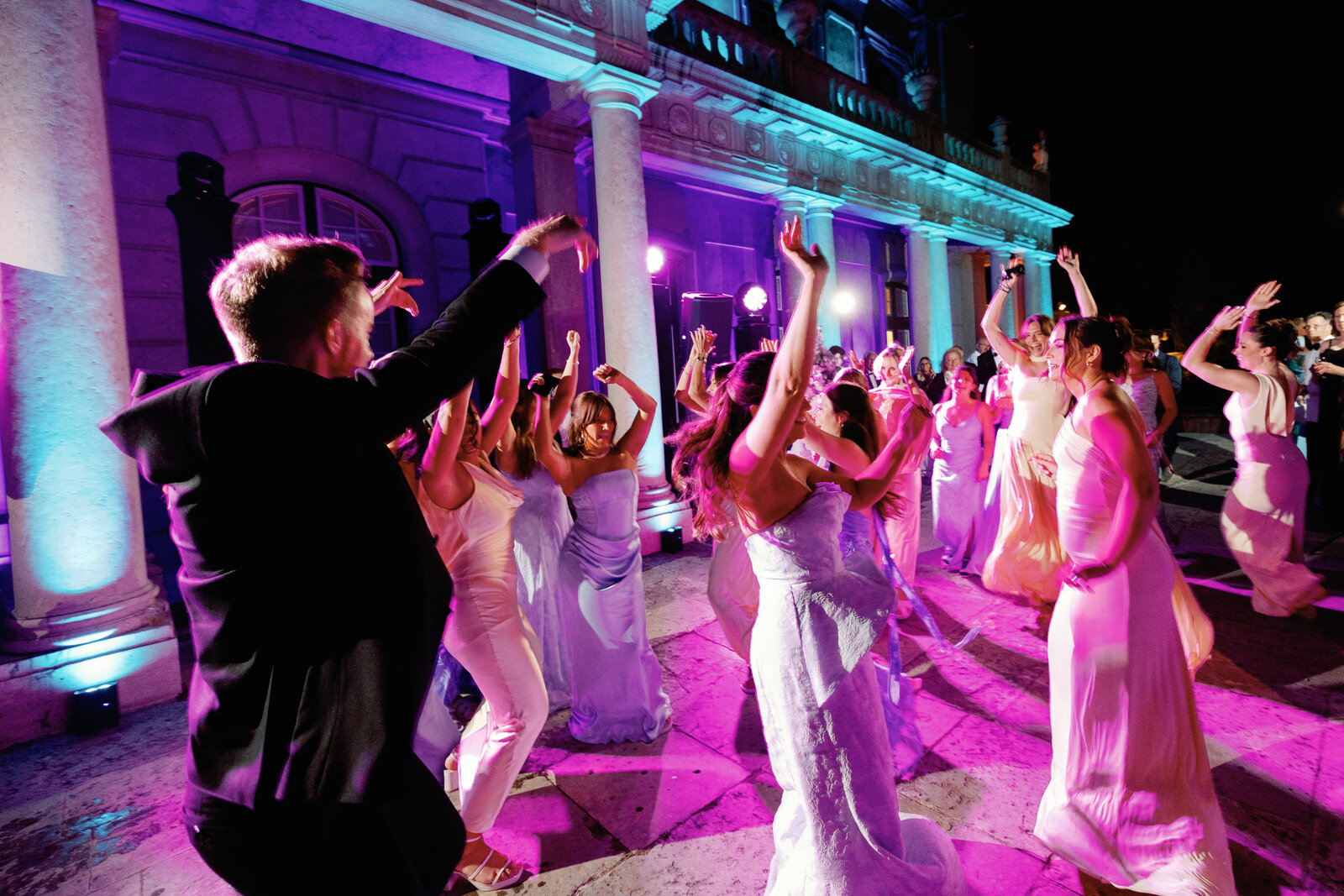Bridesmaids dancing in a circle with arms raised at night