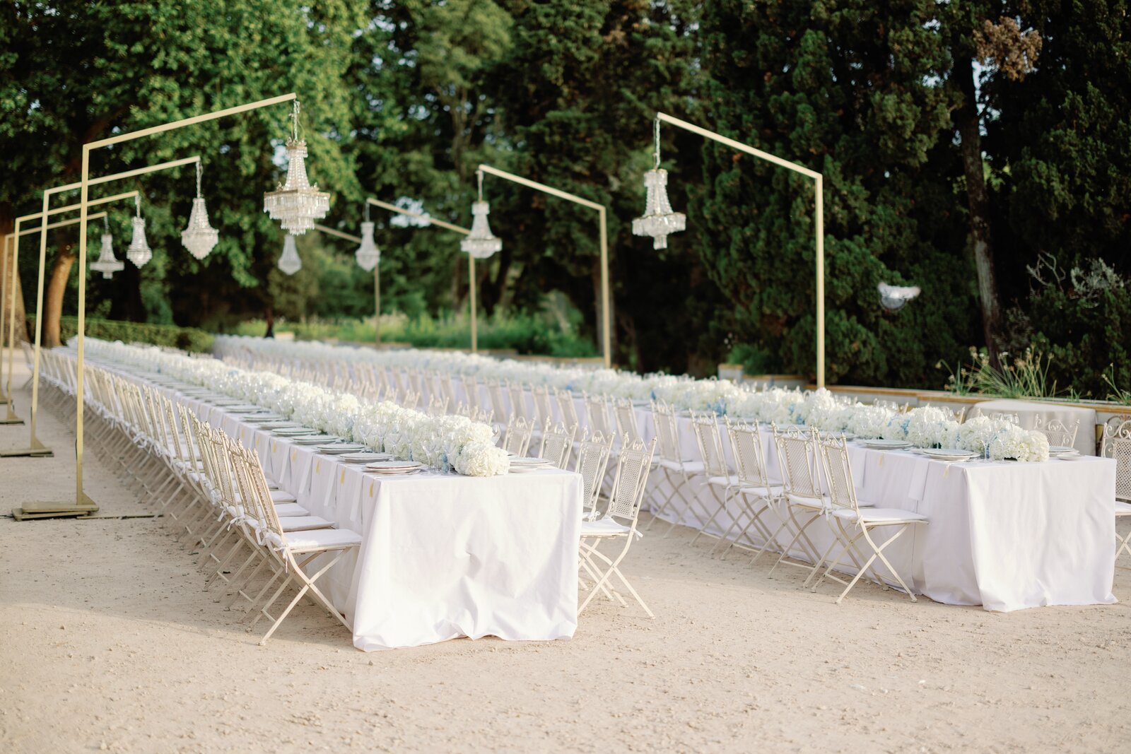 Gold frames with hanging crystal chandeliers along the cypress trees