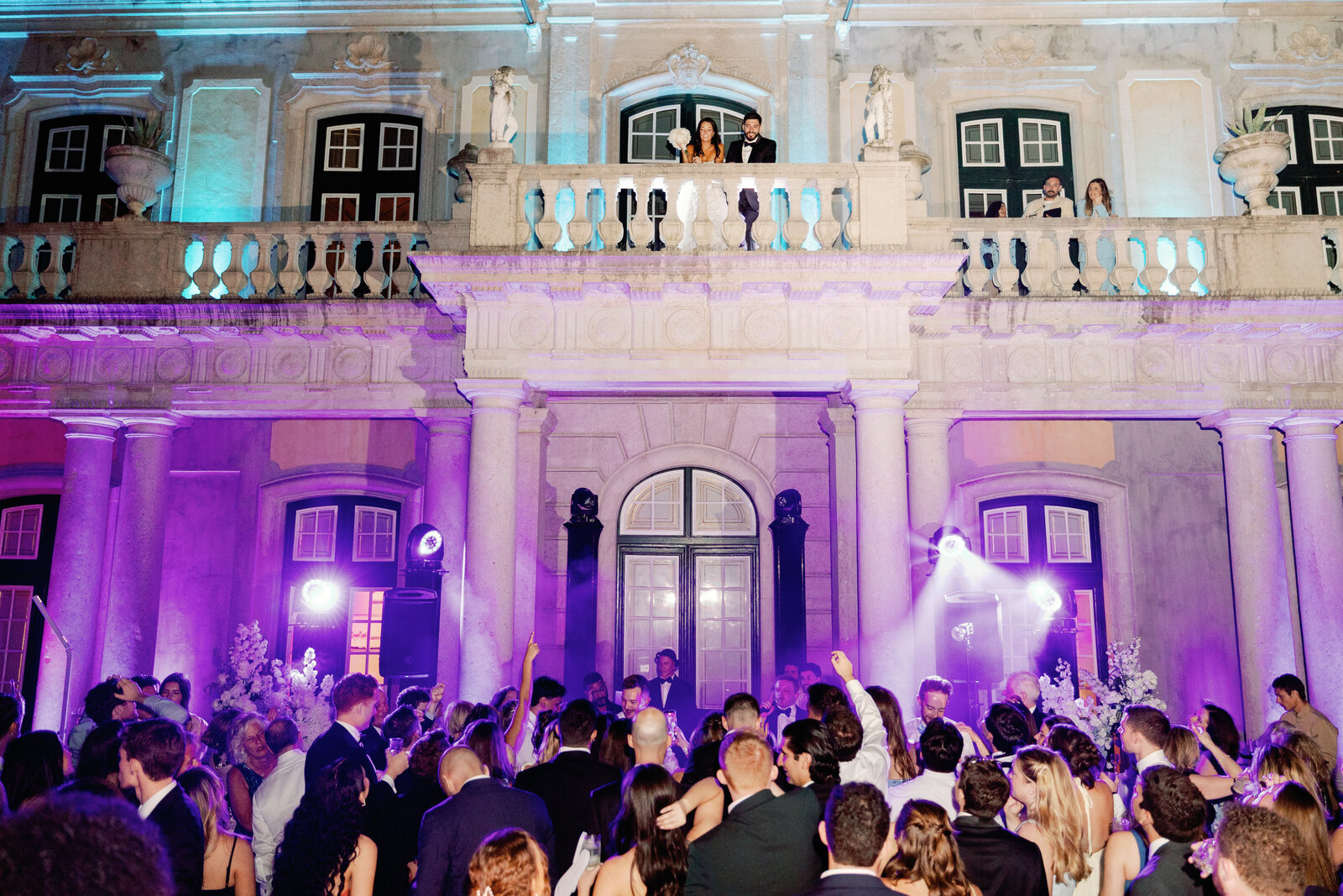 Bride and groom on the balcony overlooking the party below