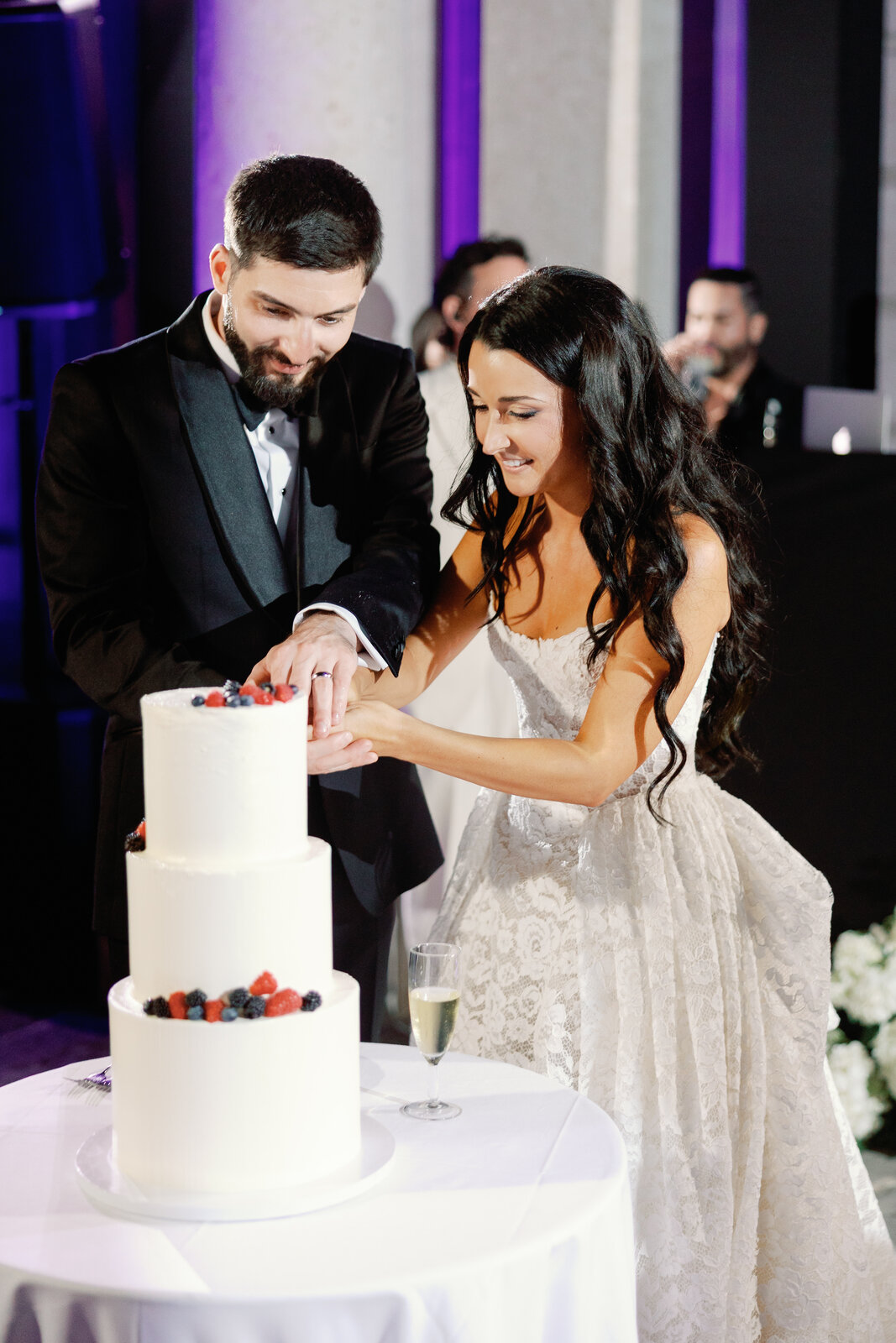Bride and groom cutting the berry-topped wedding cake together