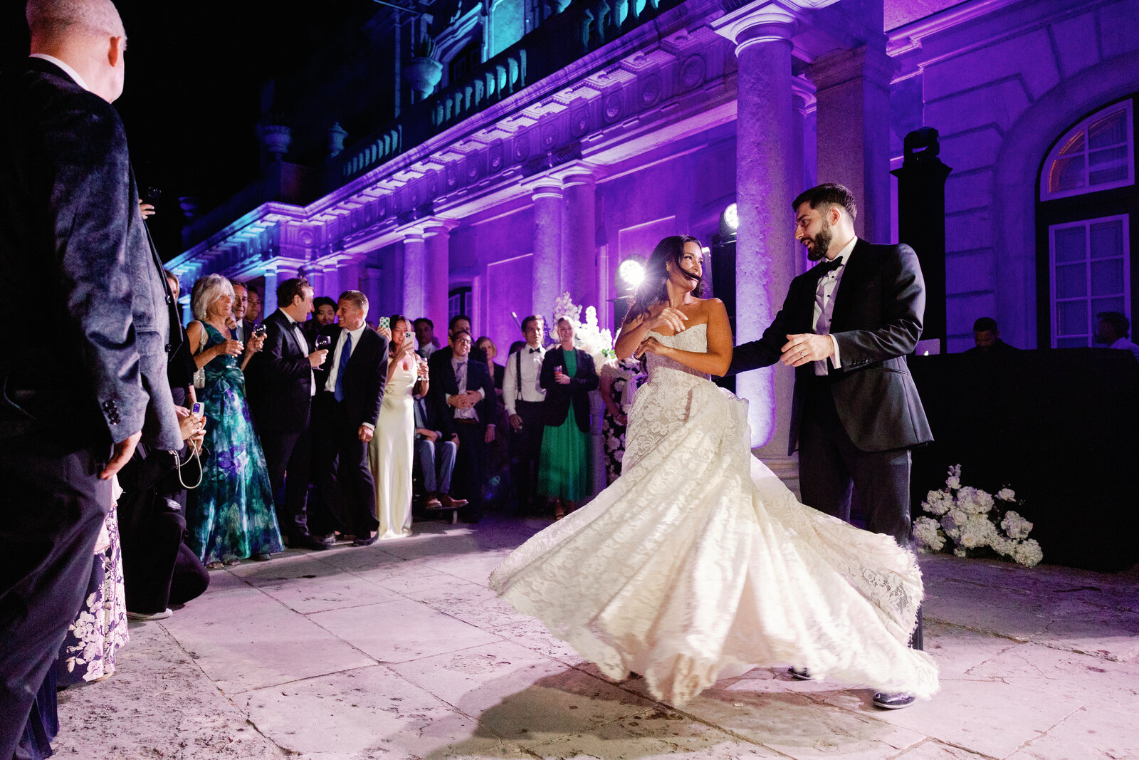 Bride's dress swirling as she dances while guests look on