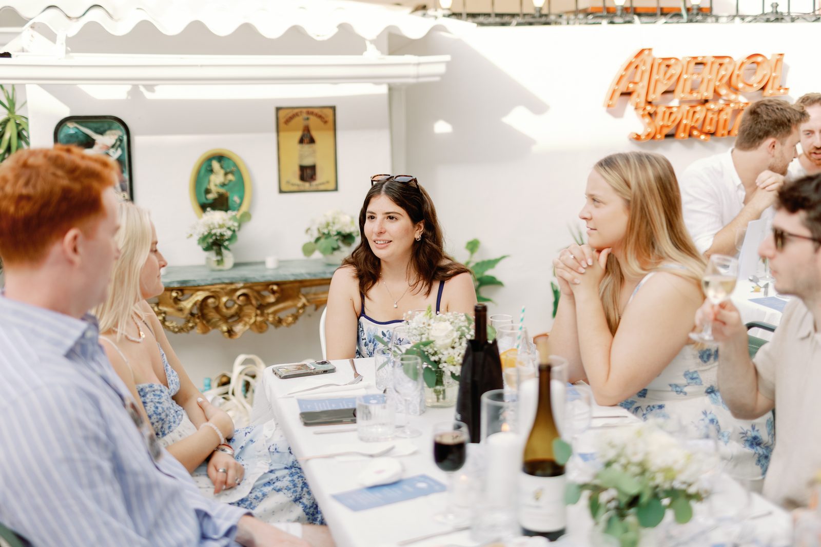 Guests chatting at the table near the Aperol sign